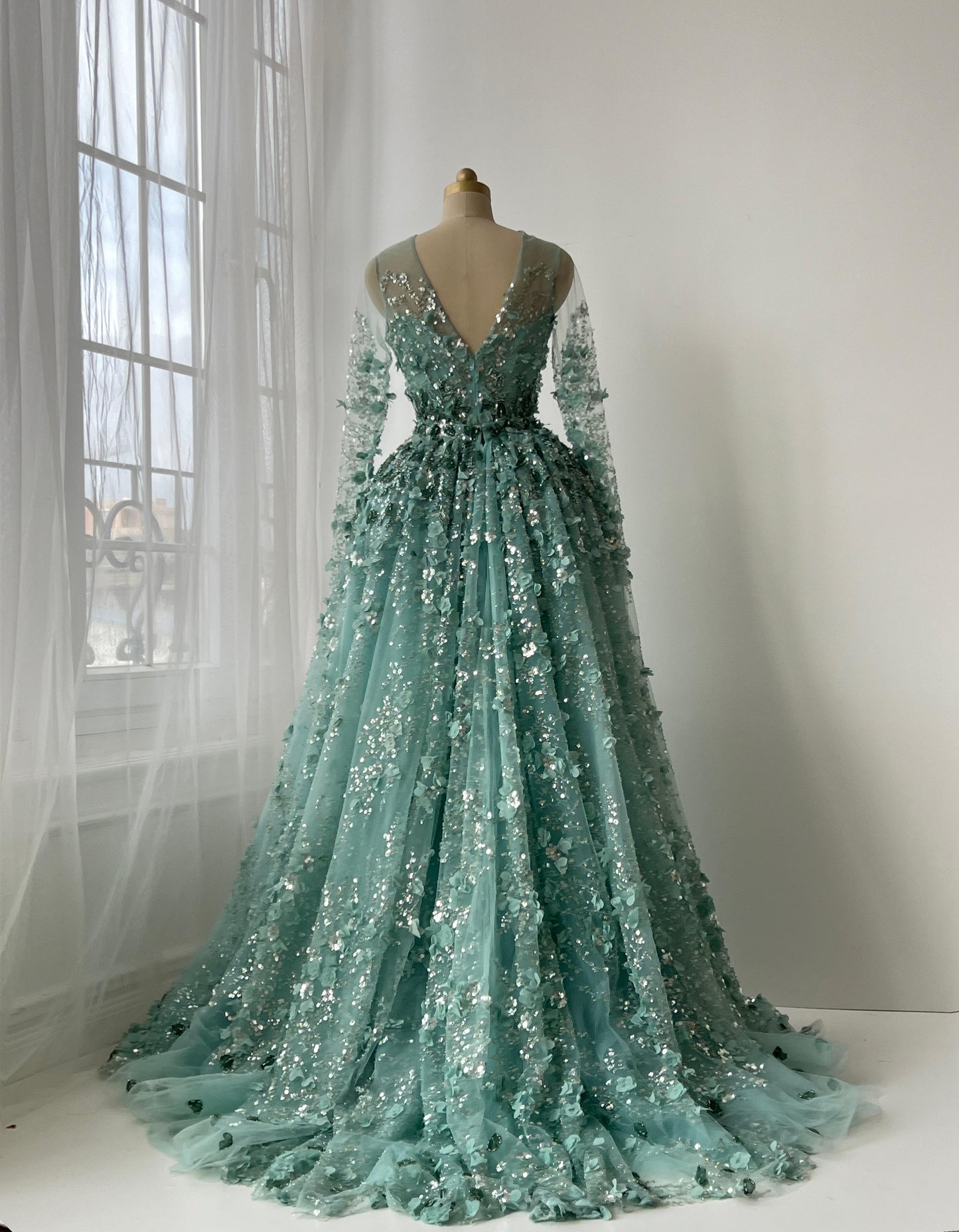 Turquoise A-Line gown with floral and sequin details, long sleeves and overskirt