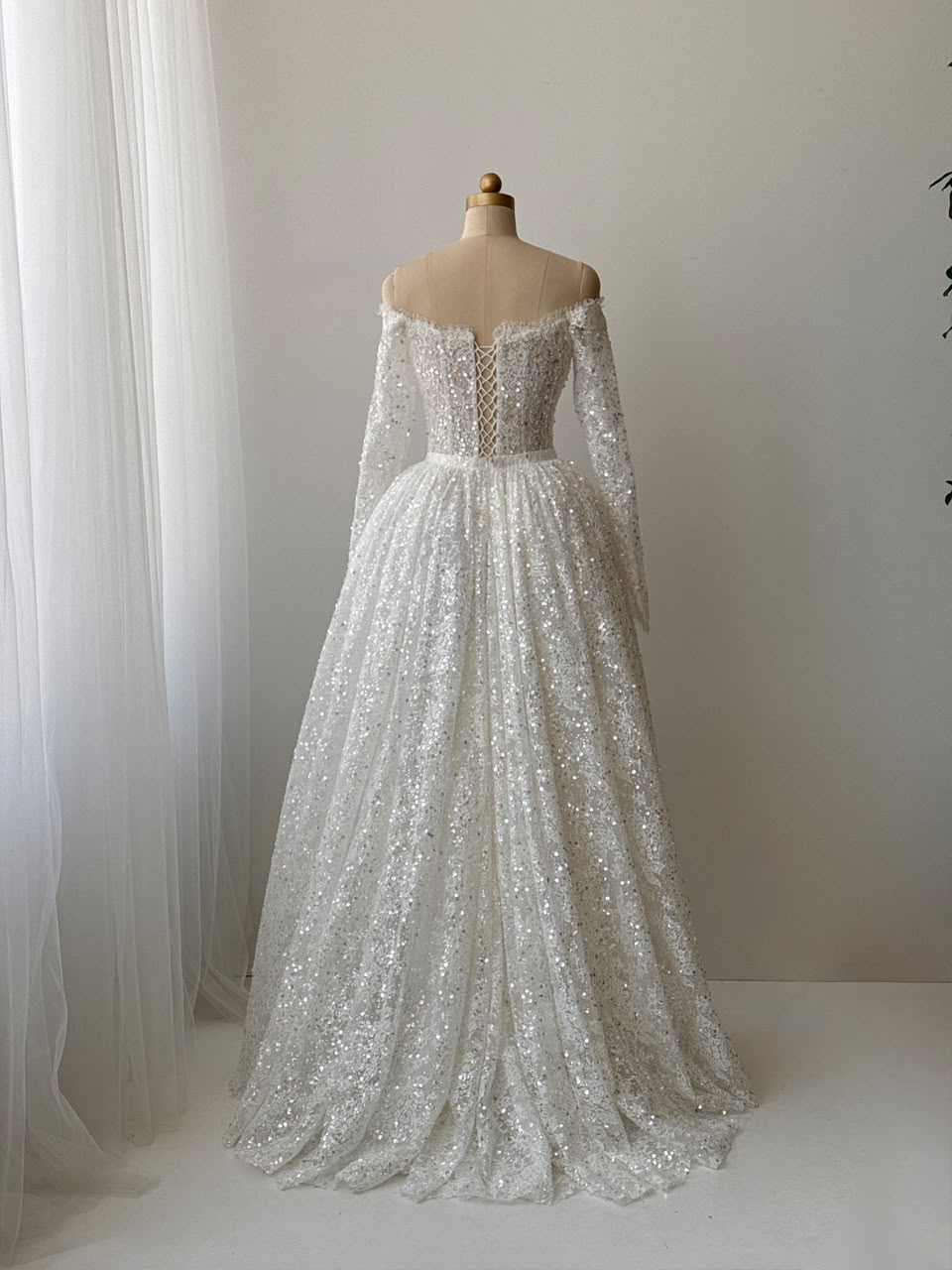 White A-Line bridal gown with long off the shoulder sleeves, sequins, detachable overskirt and embroidered bows