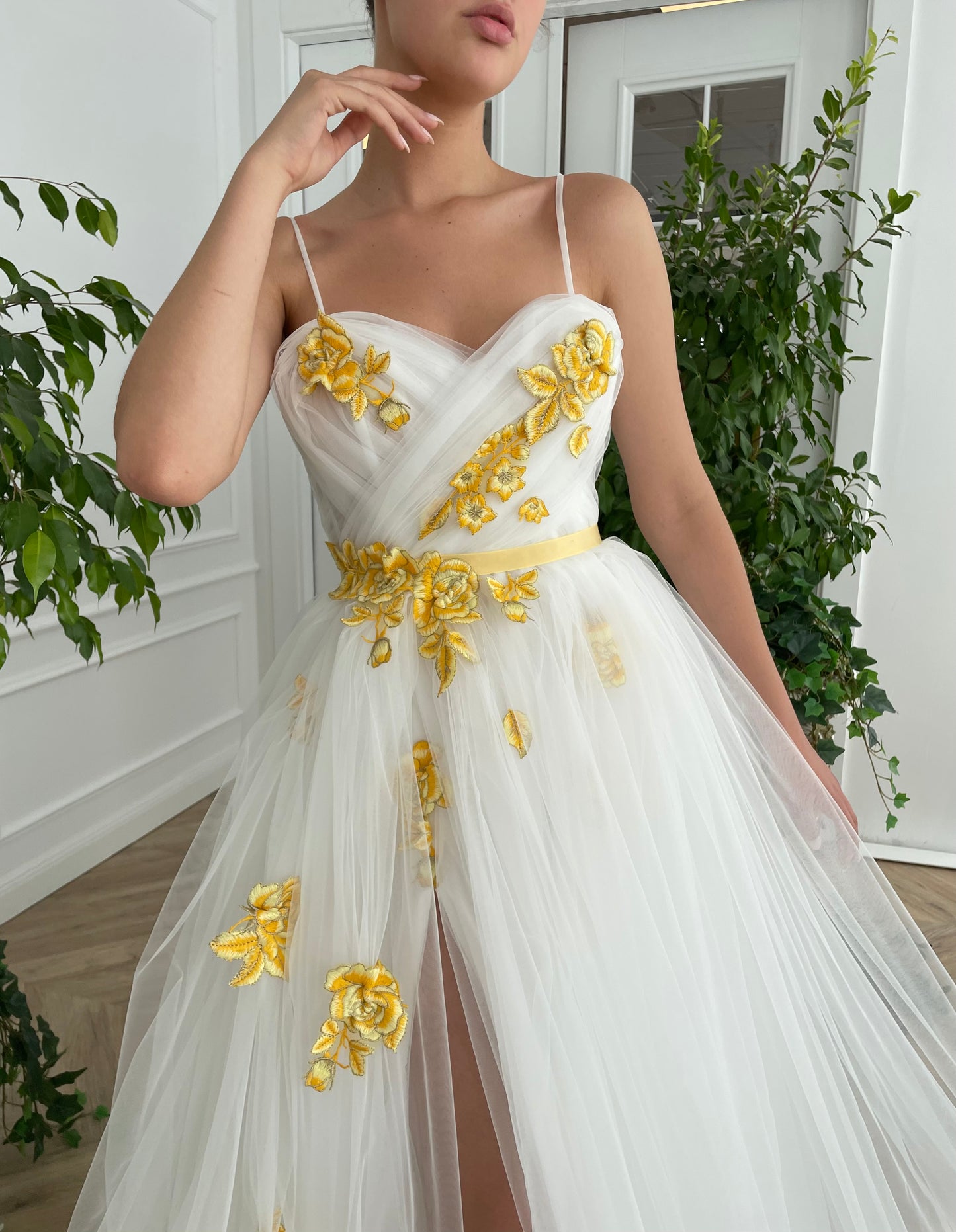 A line white bridal dress with spaghetti straps, embroidered flowers and slit