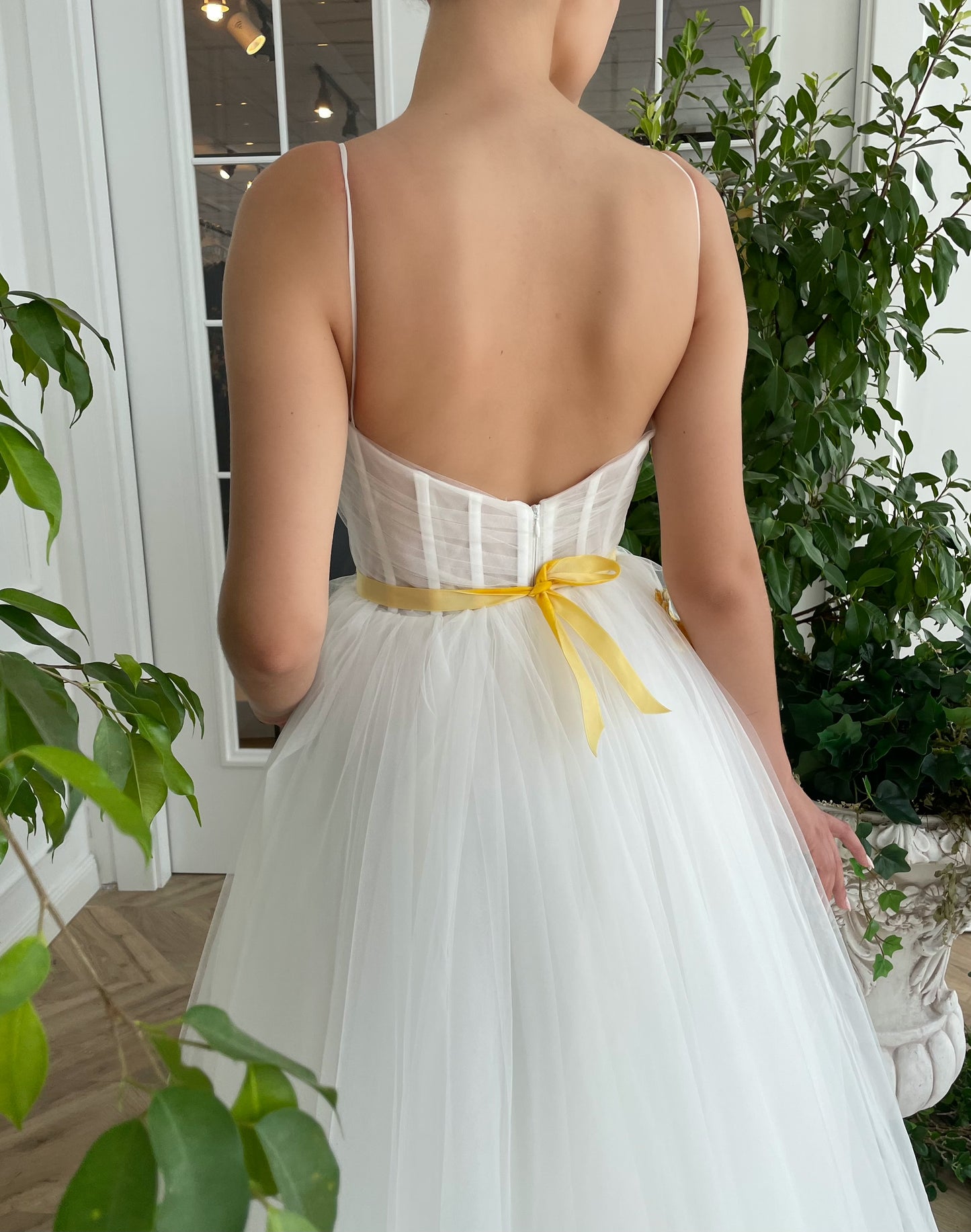 A line white bridal dress with spaghetti straps, embroidered flowers and slit