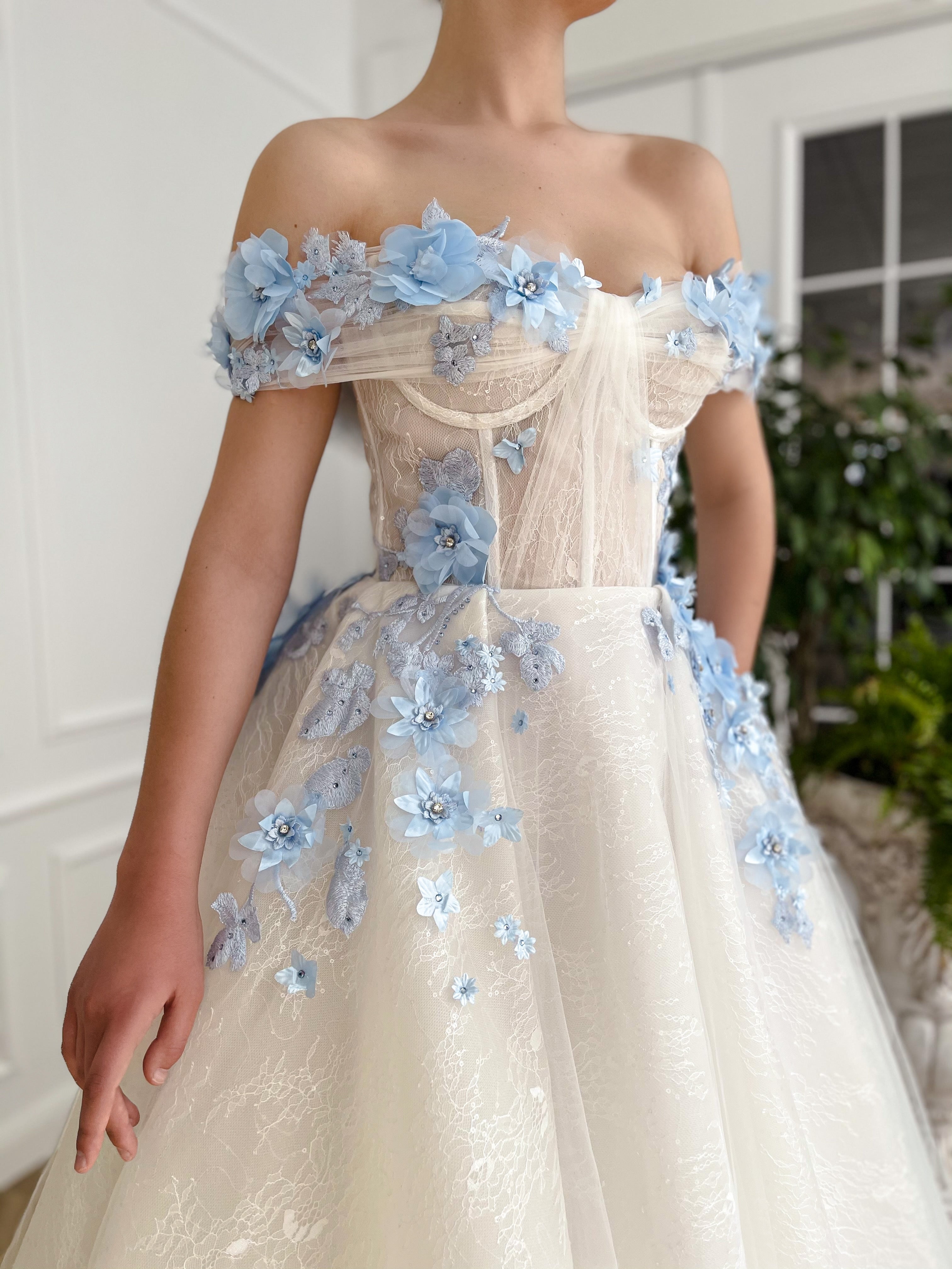 A line white bridal dress with off the shoulder sleeves and embroidered blue flowers