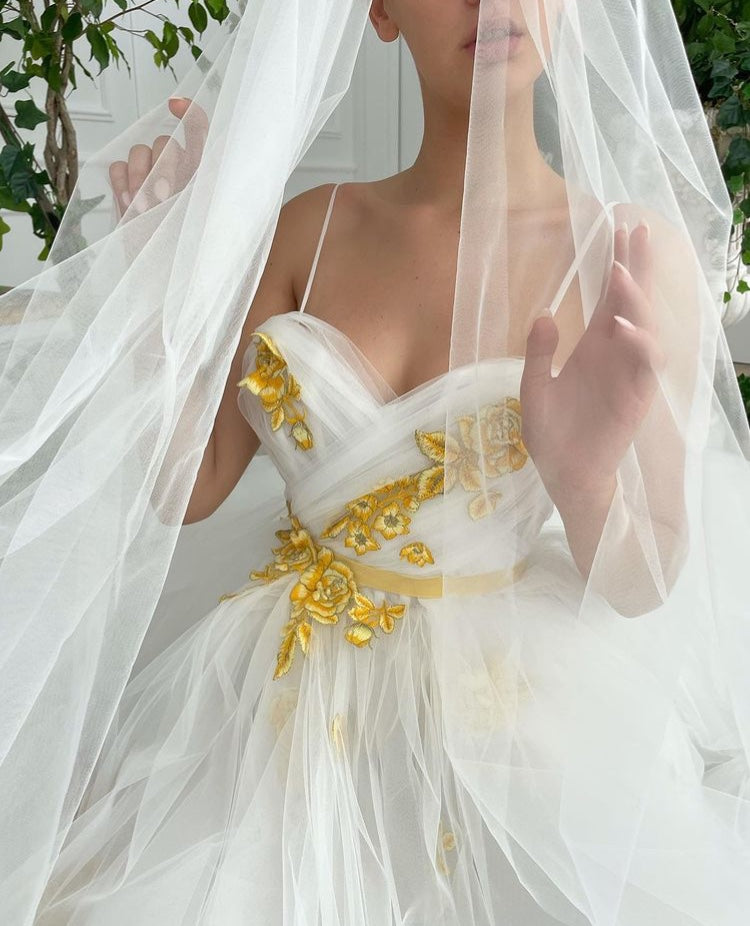 A line white bridal dress with spaghetti straps, embroidered flowers and slit