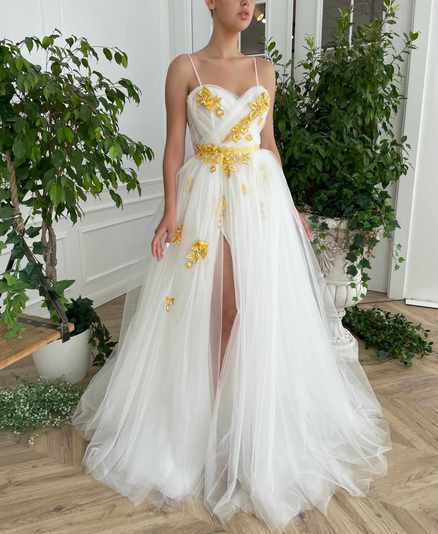 A line white bridal dress with spaghetti straps, embroidered flowers and slit