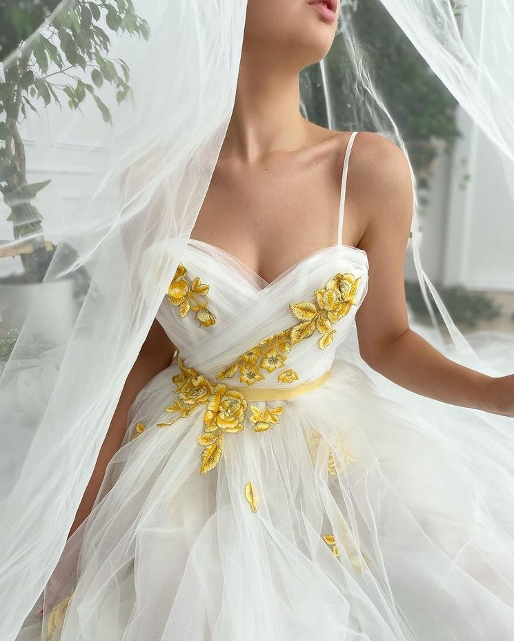 A line white bridal dress with spaghetti straps, embroidered flowers and slit