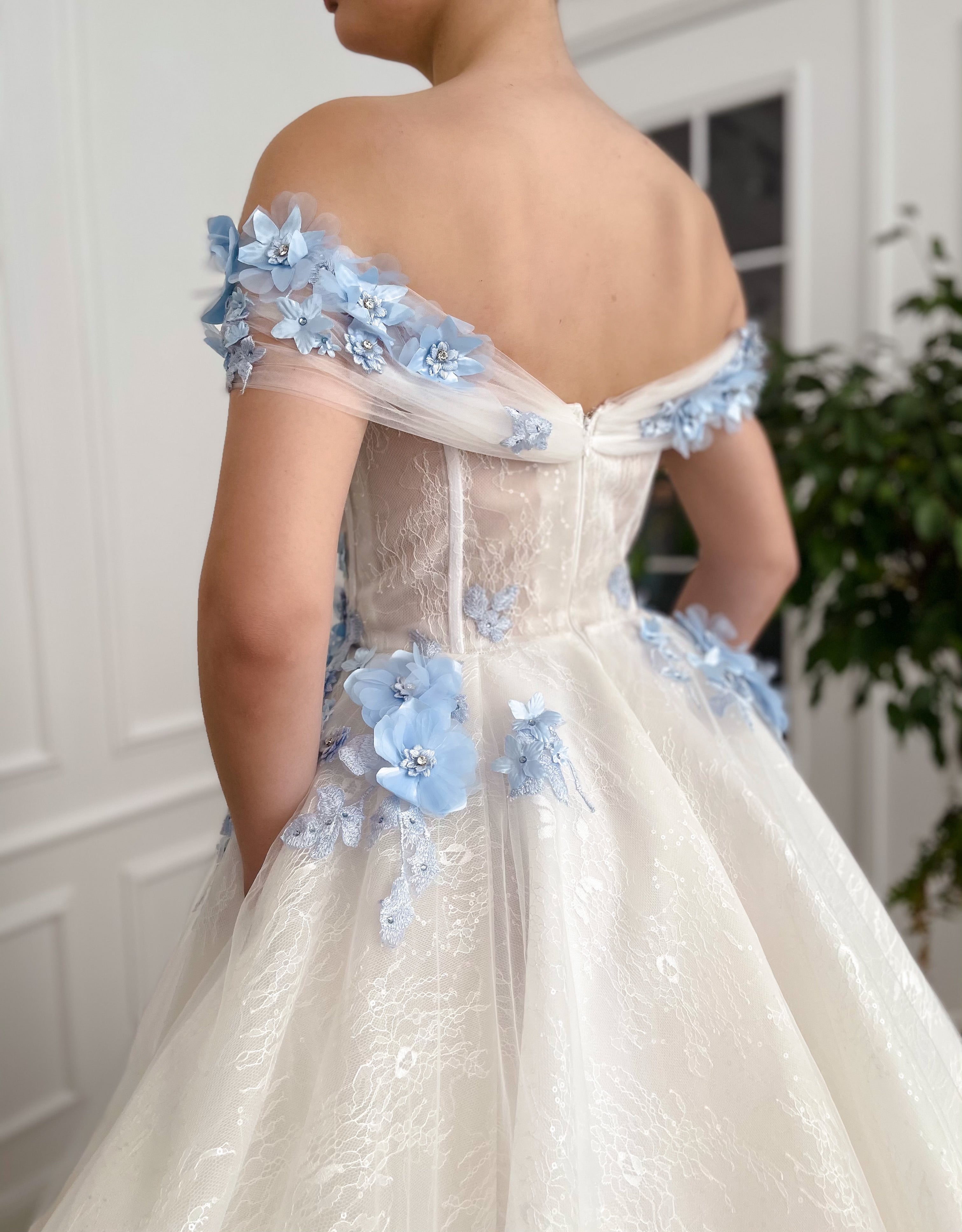 A line white bridal dress with off the shoulder sleeves and embroidered blue flowers