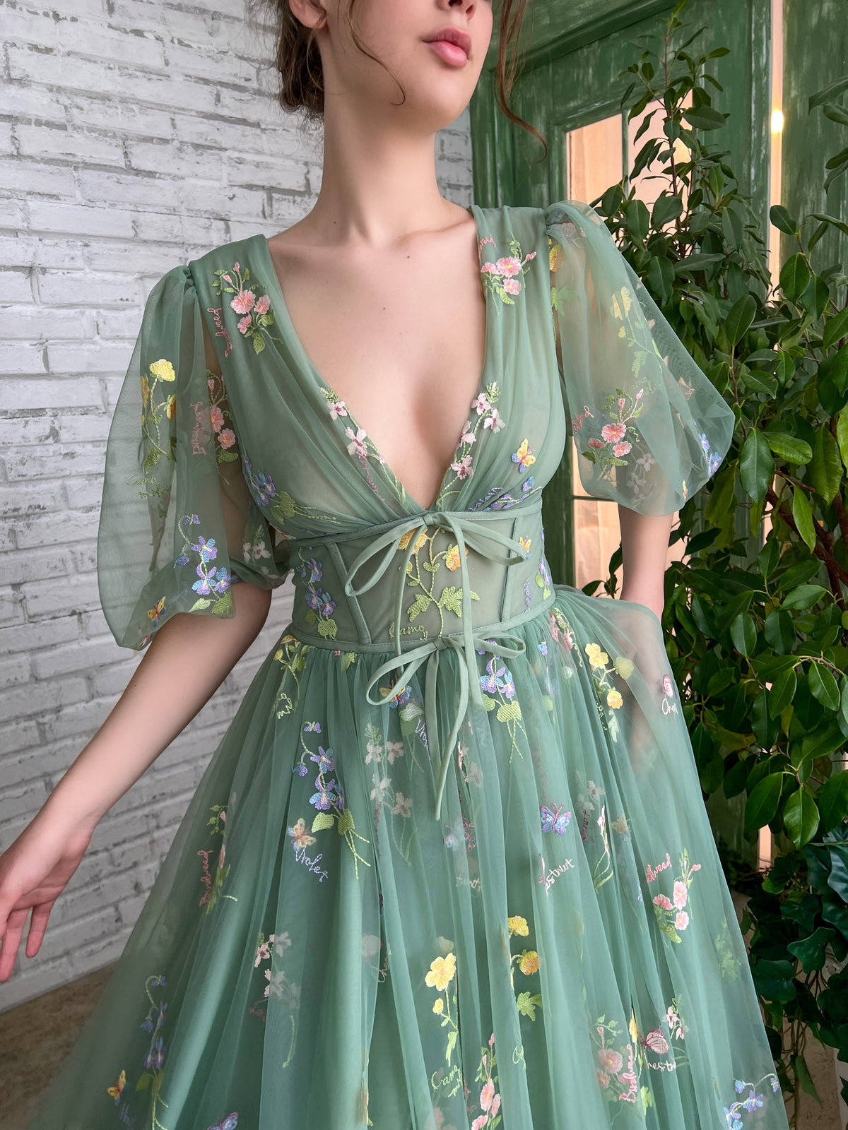 Green gown with semi-puff sleeves, a deep V-neckline, and intricate embroidered flowers