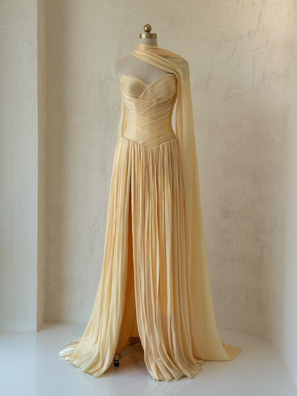 Yellow A-line gown with draped fabric, cape and no sleeves