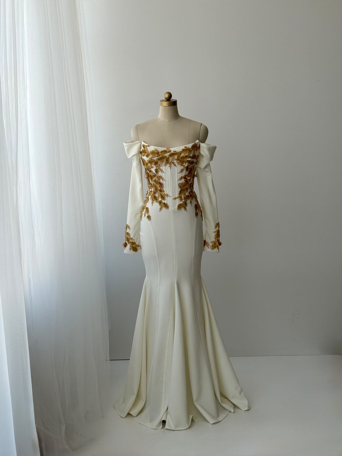 White mermaid bridal gown with long off the shoulder sleeves and gold embroidery
