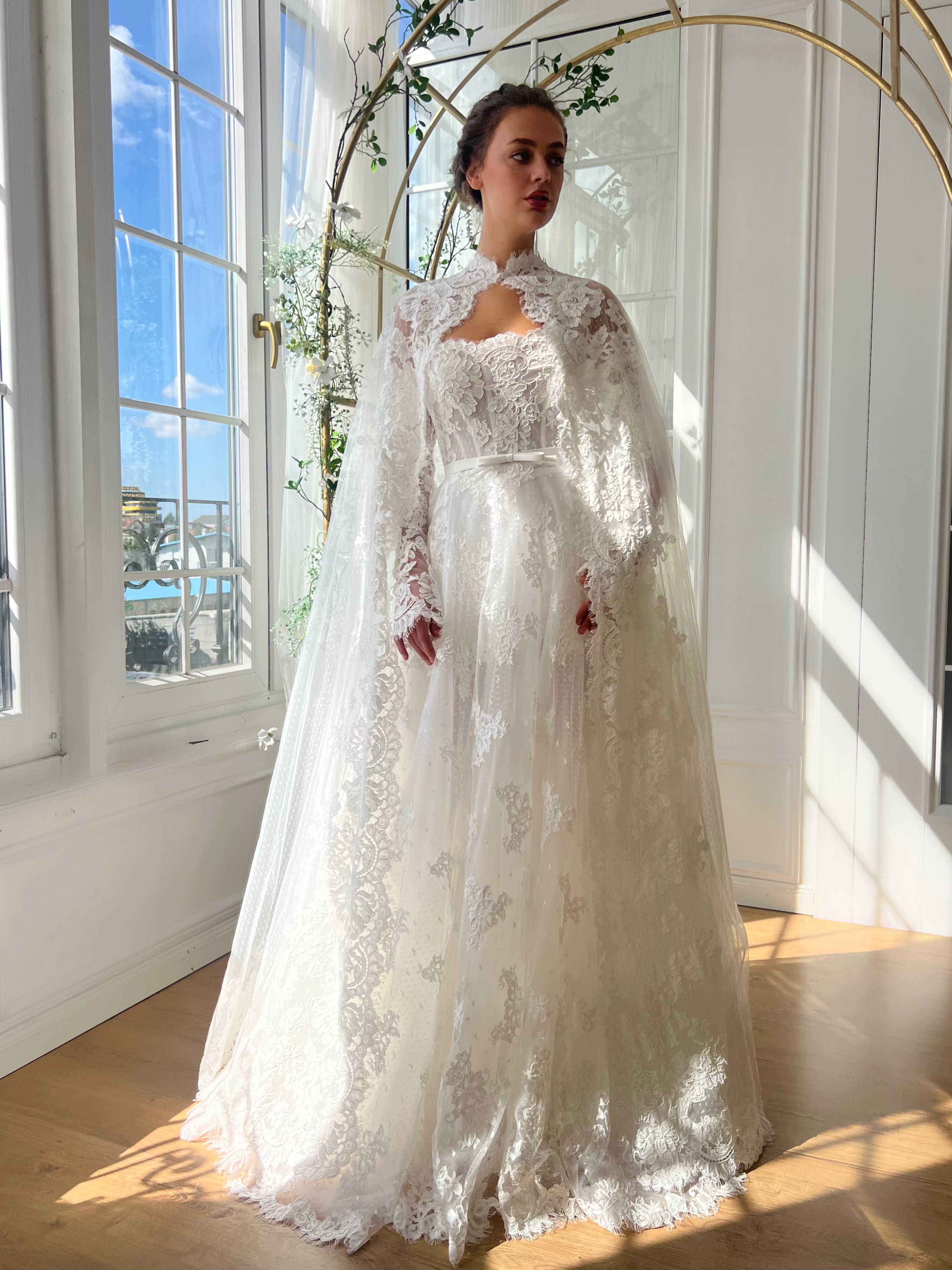 White bridal A-Line gown with long off the shoulders sleeves, cape and embroidery