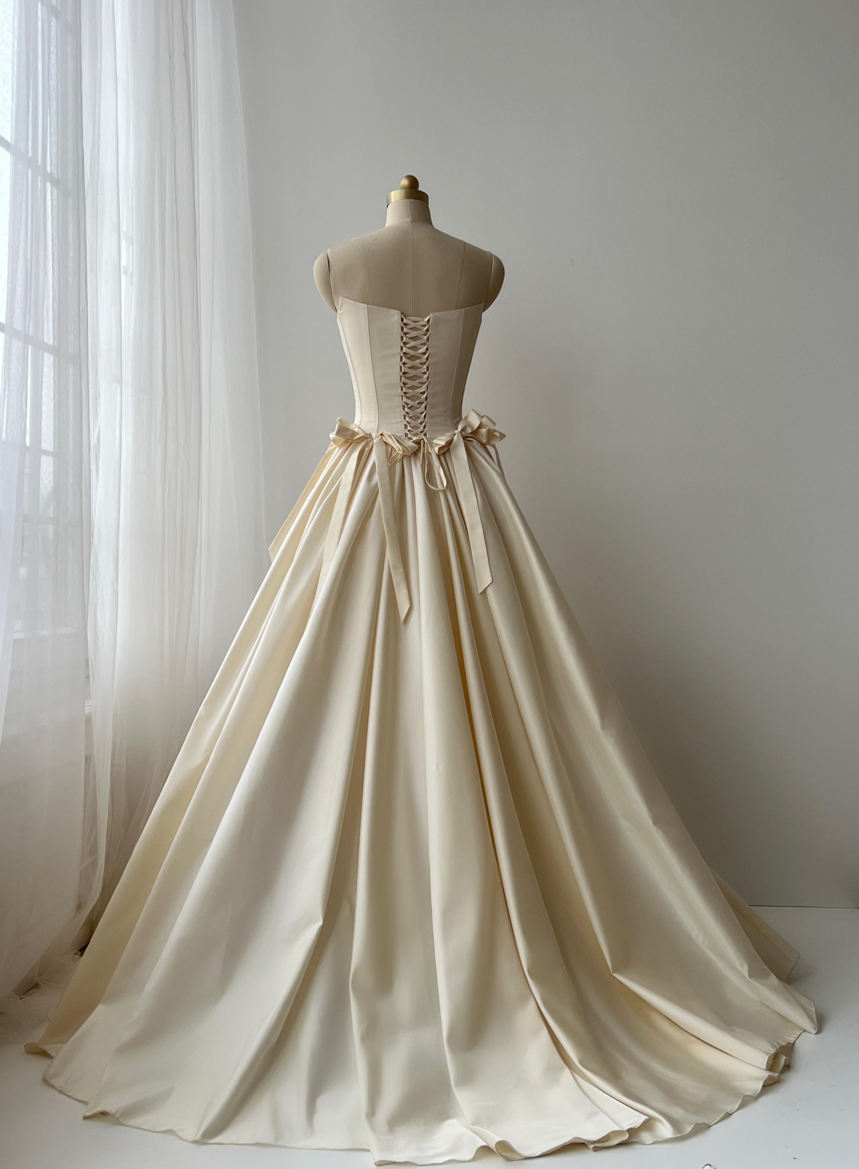 Beige A-Line bridal gown with no sleeves and embroidered bows