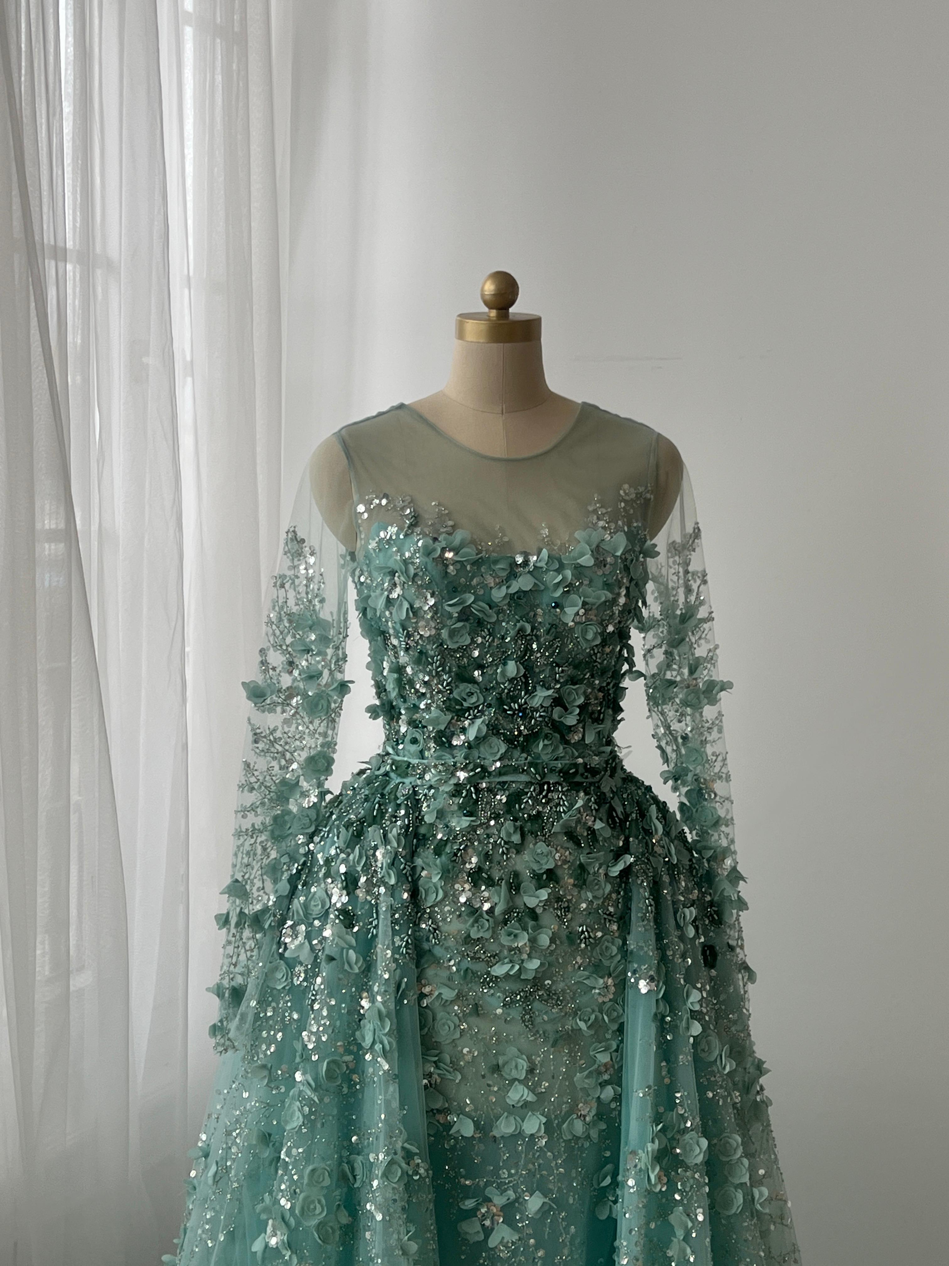 Turquoise A-Line gown with floral and sequin details, long sleeves and overskirt