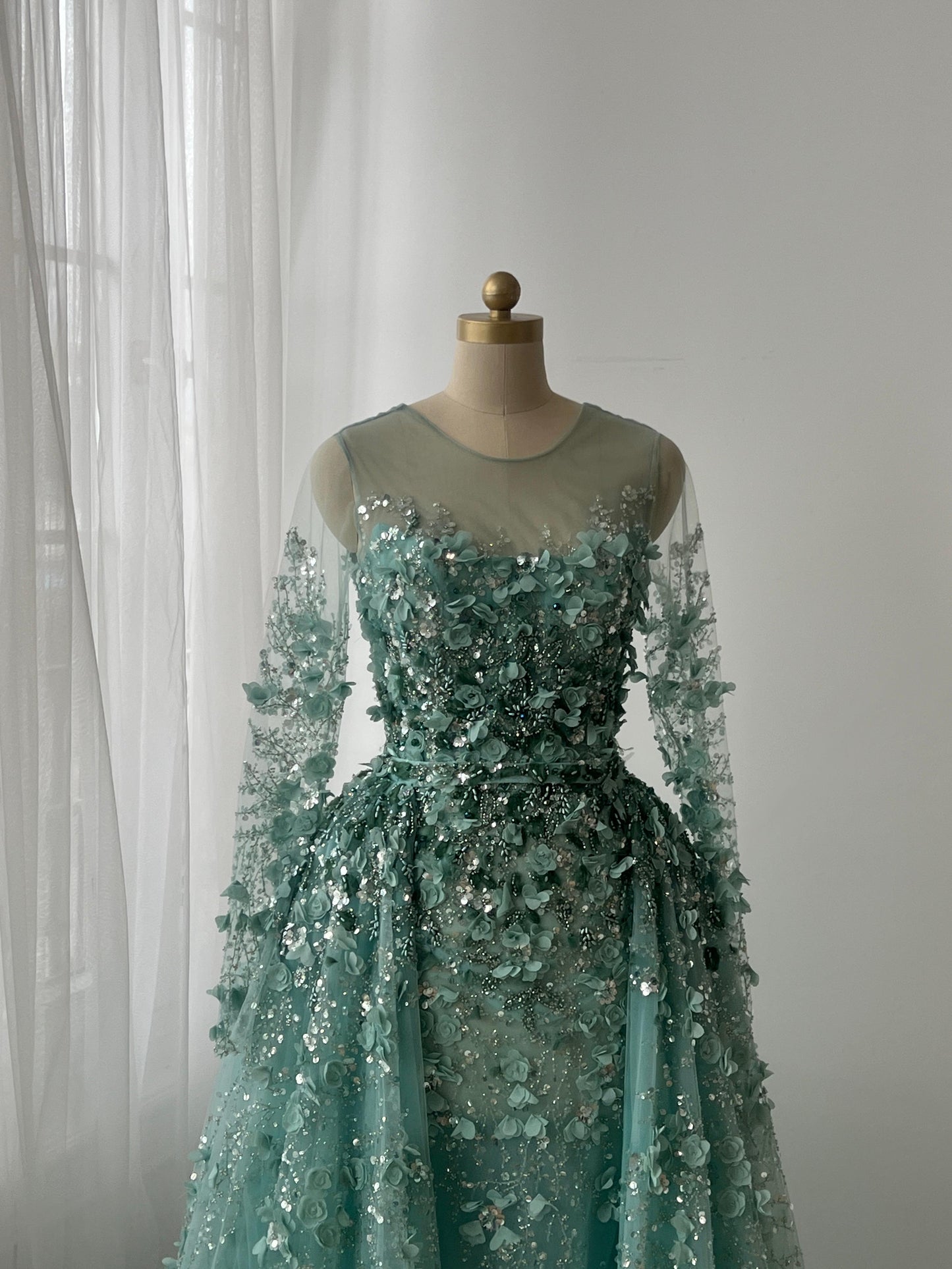 Turquoise A-Line gown with floral and sequin details, long sleeves and overskirt