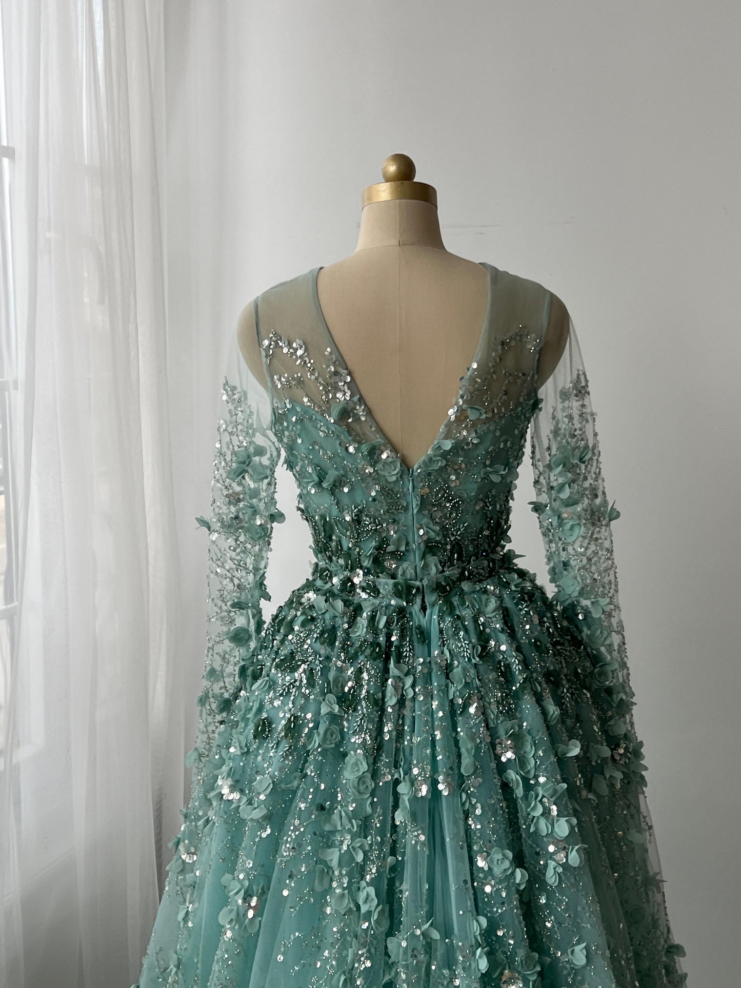 Turquoise A-Line gown with floral and sequin details, long sleeves and overskirt