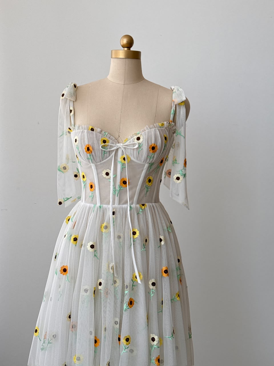 White midi dress with bow straps and embroidered colorful flowers