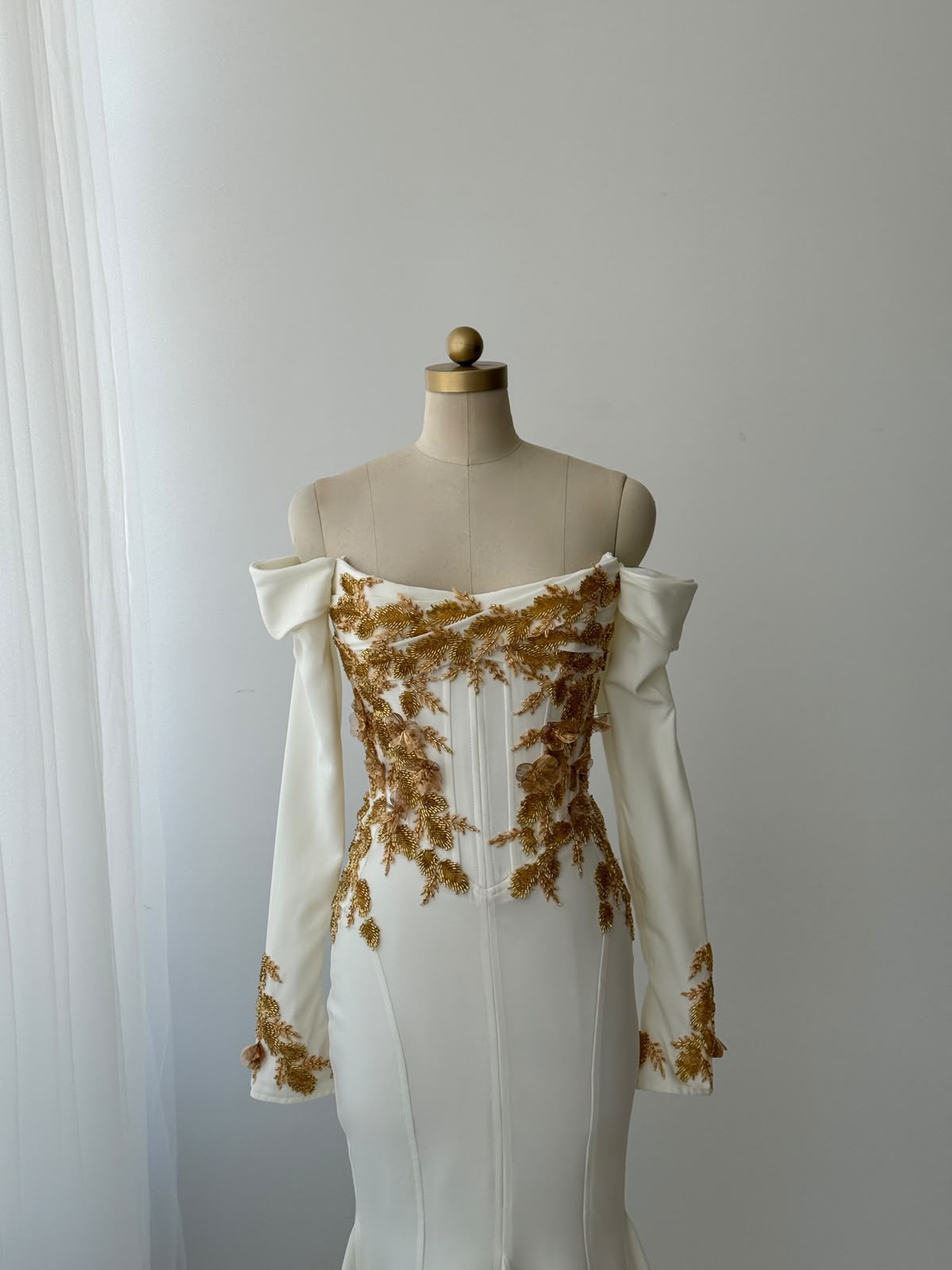 White mermaid bridal gown with long off the shoulder sleeves and gold embroidery