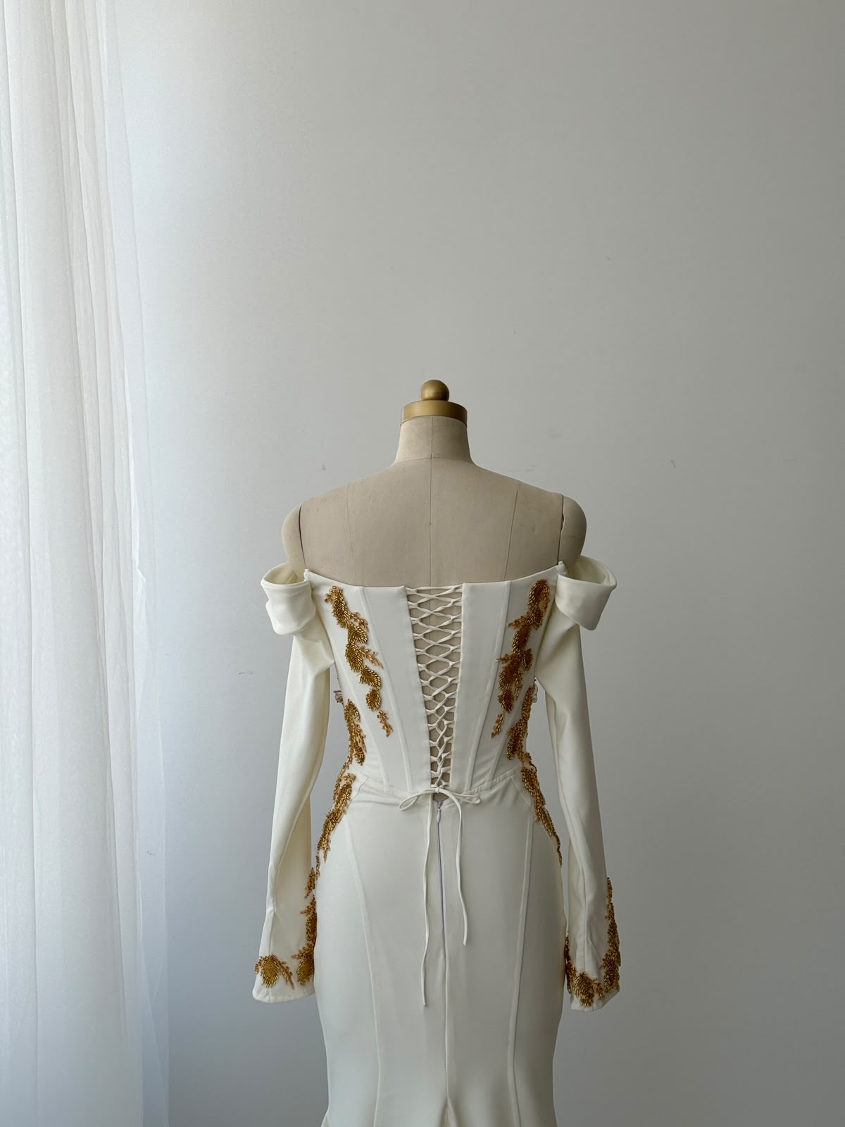 White mermaid bridal gown with long off the shoulder sleeves and gold embroidery