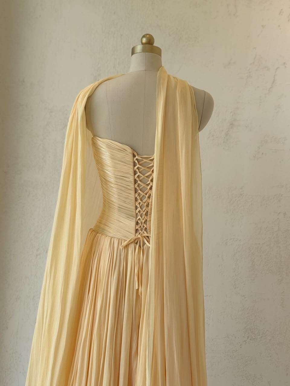 Yellow A-Line gown with draped fabric, cape and no sleeves