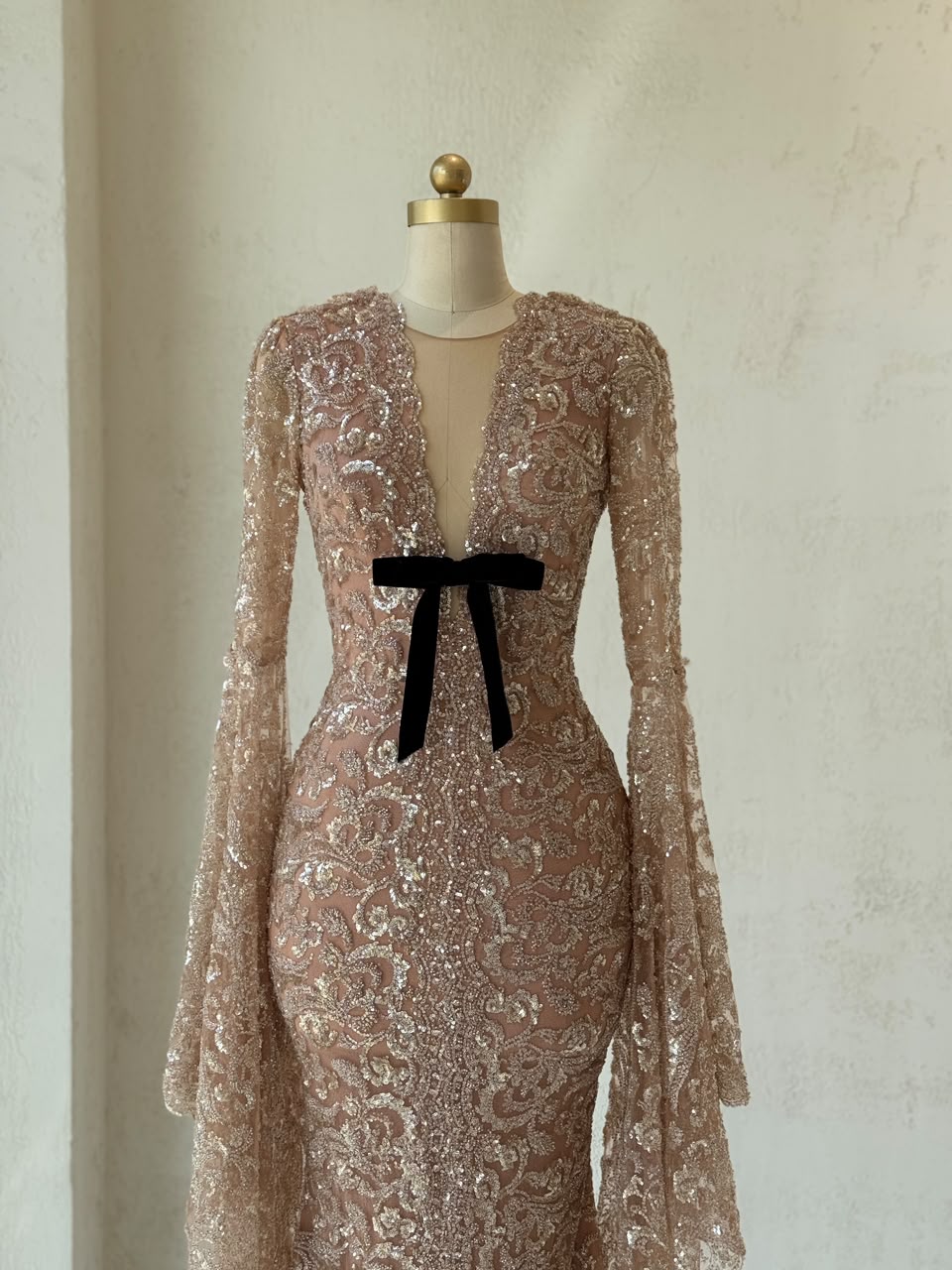 Rose gold mermaid gown with v-neck, embroidered bow, long flutter sleeves and sequins