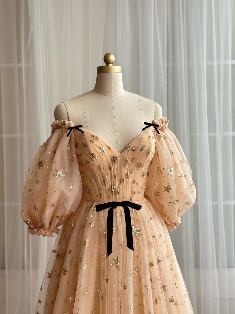 Gold A-Line dress with long off the shoulder sleeves, embroidered bows, v-neck and starry tulle fabric