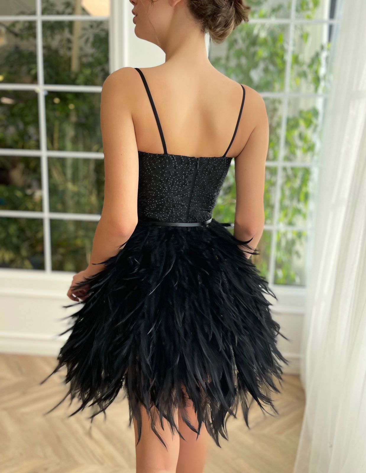 Black mini dress with spaghetti straps, belt and feathers