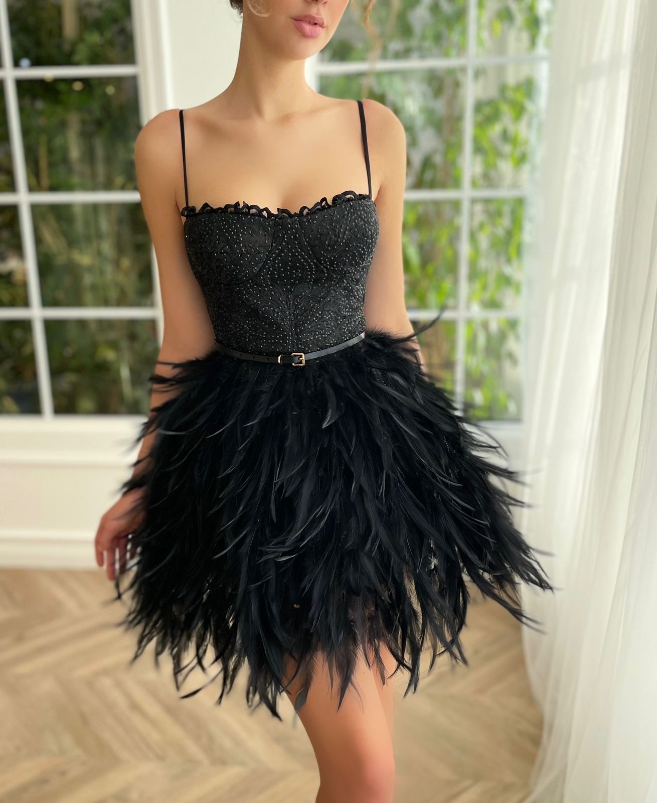 Black mini dress with spaghetti straps, belt and feathers