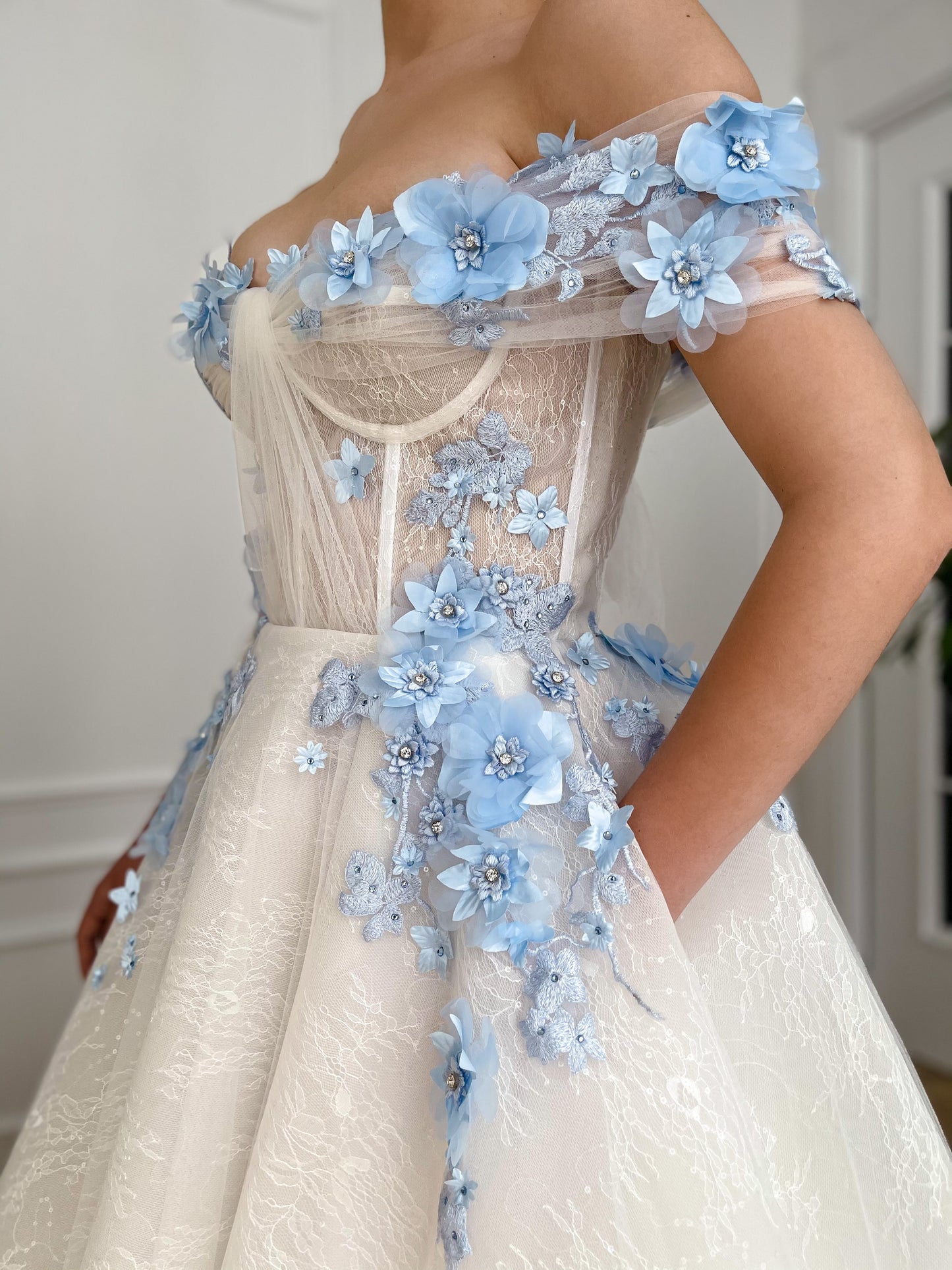 A line white bridal dress with off the shoulder sleeves and embroidered blue flowers