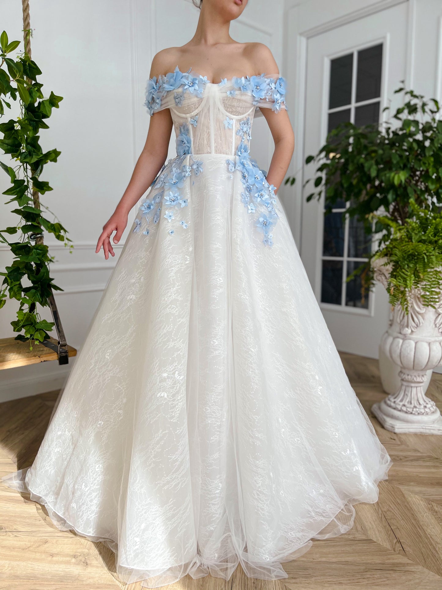 A line white bridal dress with off the shoulder sleeves and embroidered blue flowers
