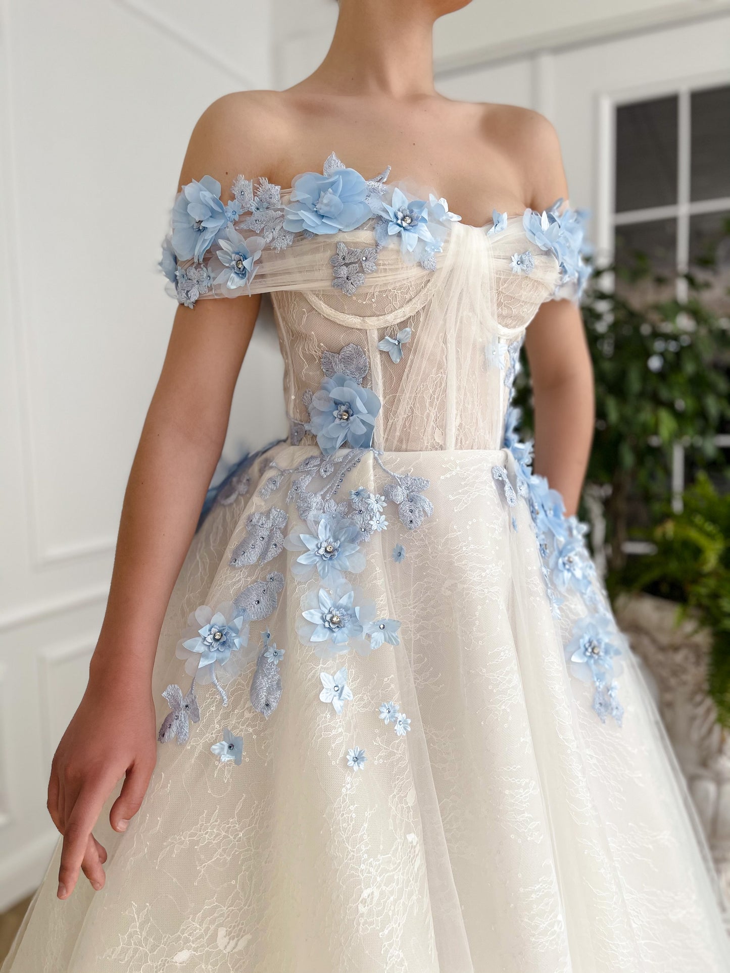 A line white bridal dress with off the shoulder sleeves and embroidered blue flowers