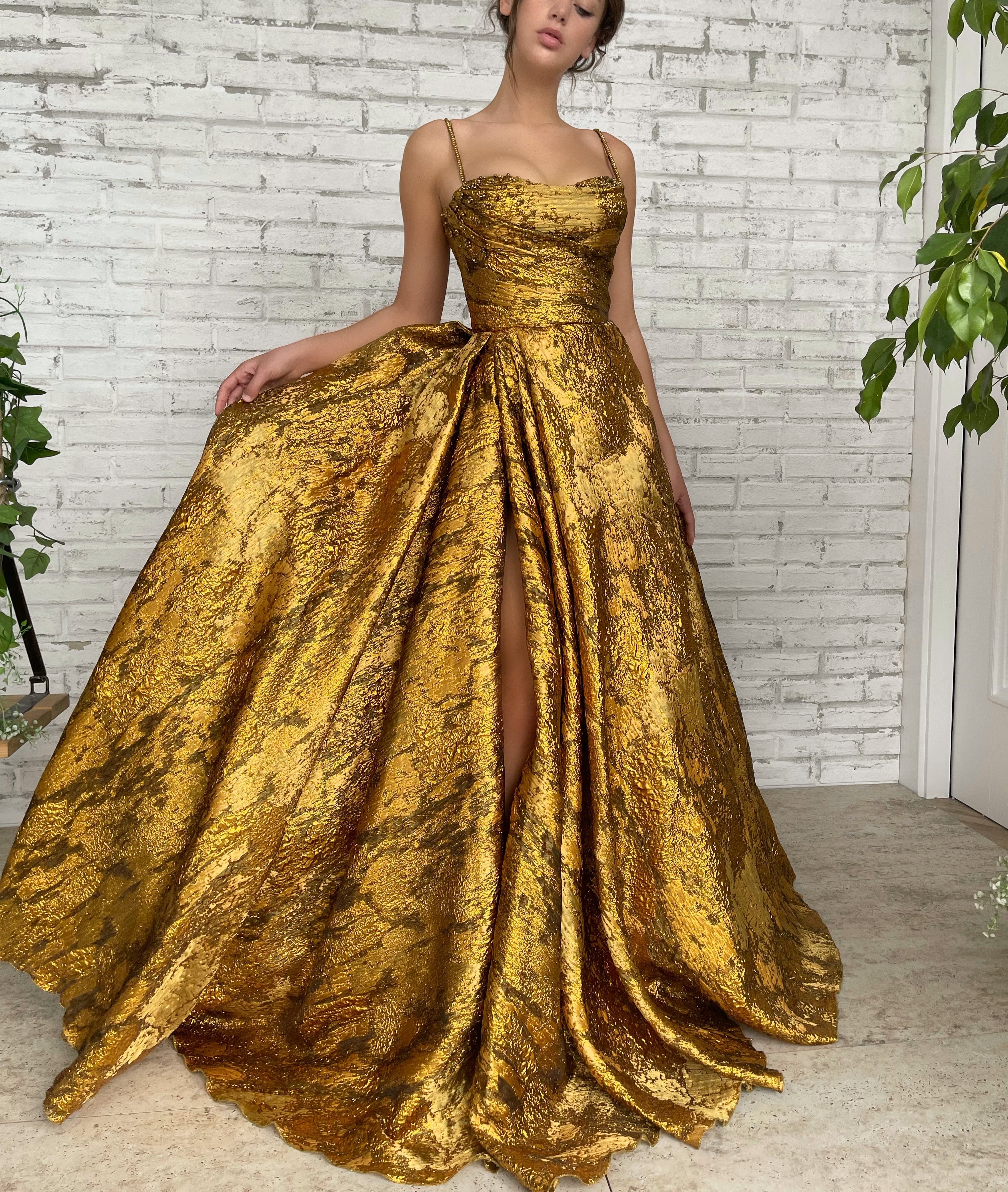 Fashion Model in Golden Dress. Woman in Long Evening Gown with Gold Jewelry  and Wavy Hairstyle over Gray Wall Background Stock Photo | Adobe Stock