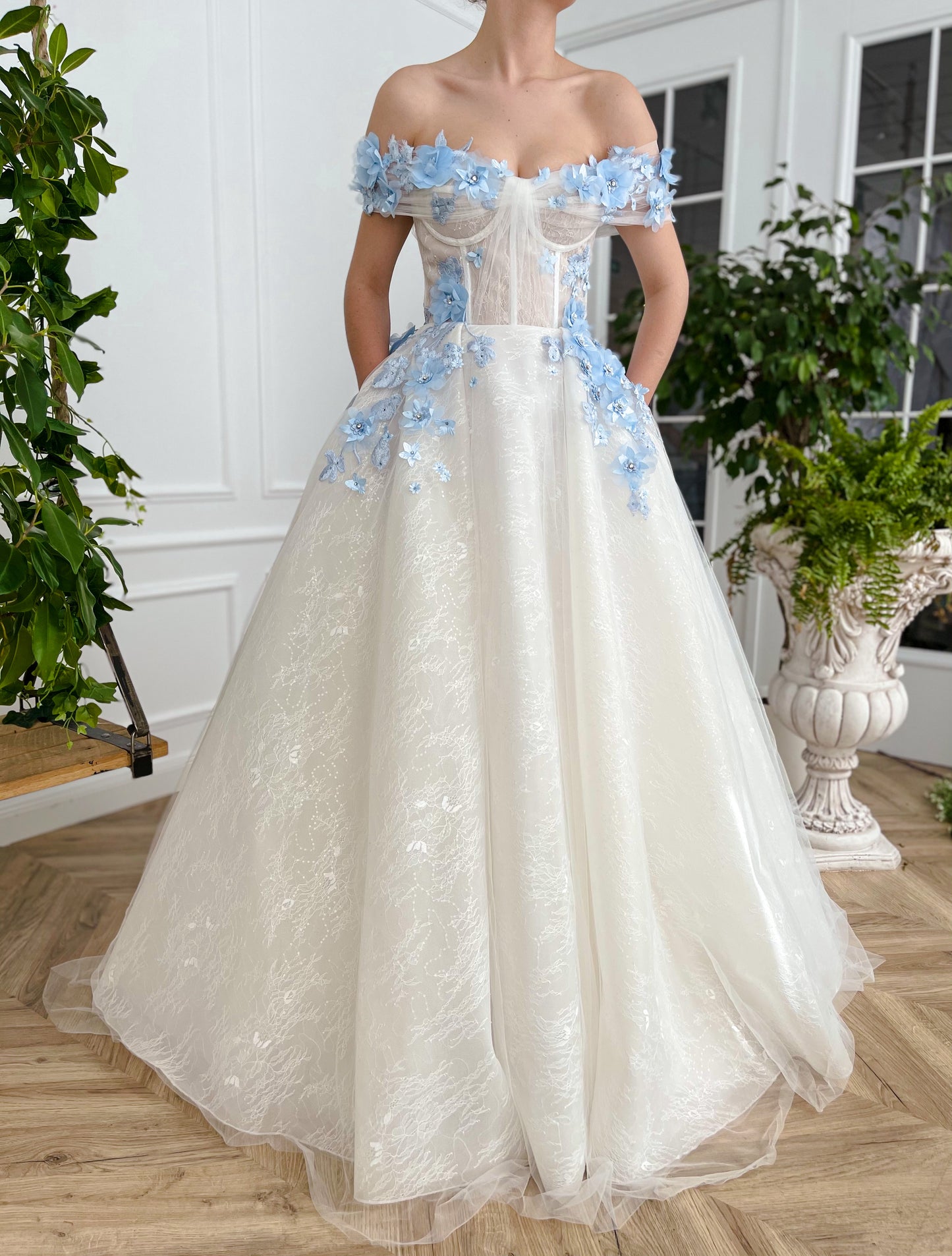 A line white bridal dress with off the shoulder sleeves and embroidered blue flowers